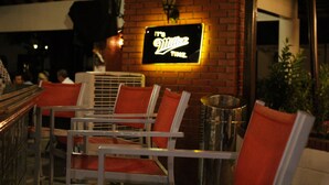 A restaurant with a neon sign that reads "It's Villa's Time." There are several metal chairs with orange cushions and a brick wall in the background. - Gran Hotel Nacional (David)