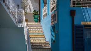 Una escalera con baldosas estampadas que lleva a un edificio de fachada azul y un letrero que dice "PIZZA".
