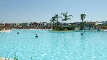 Swimmers enjoy the resort's large pool with multiple lanes, surrounded by lounge chairs and umbrellas.