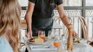 Een restaurantscène, een ober serveert eten aan een gast.