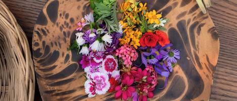 A wooden table with a variety of fresh vegetables and colorful flowers.