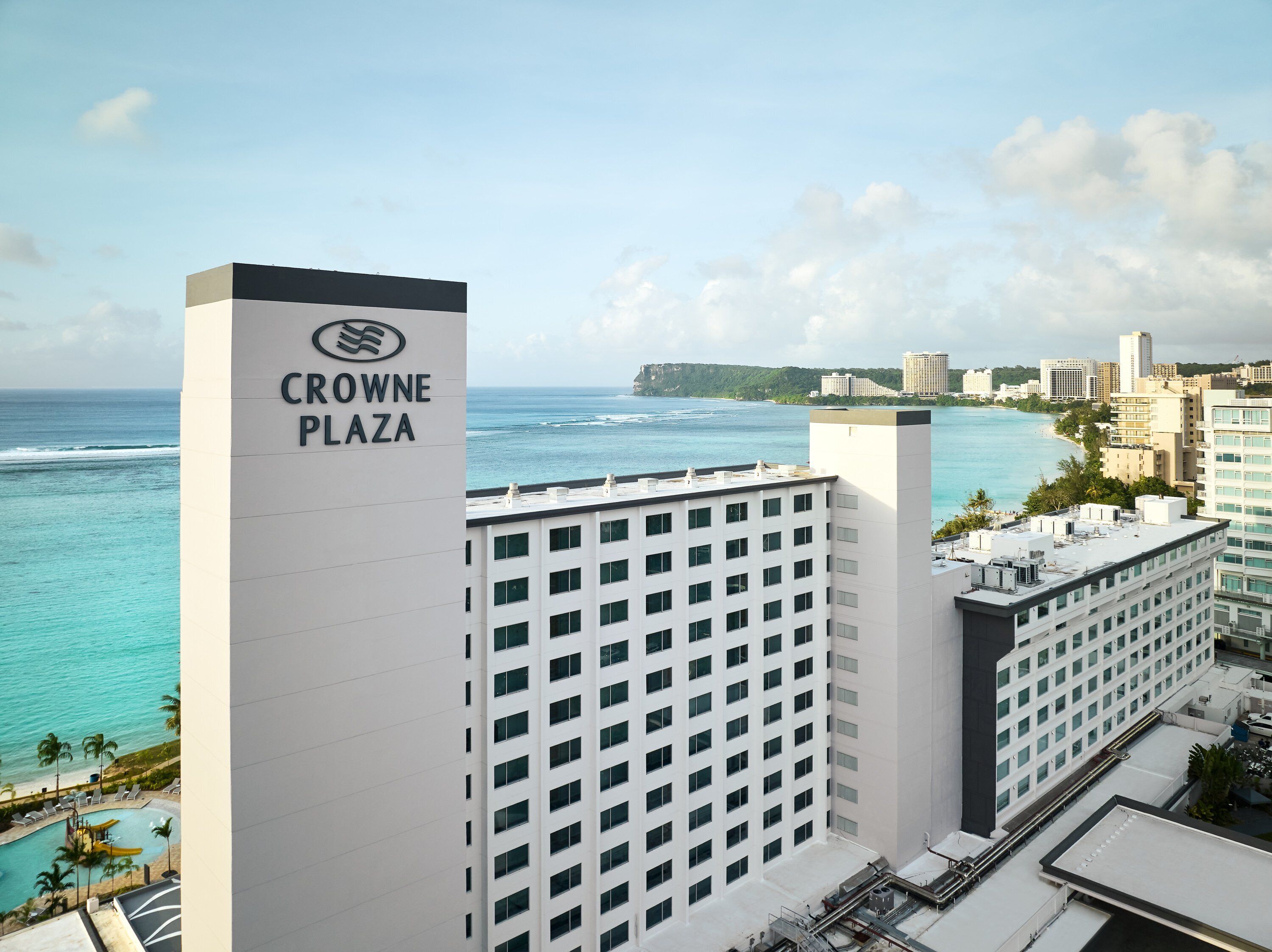 A high-rise hotel with a view of the ocean and a sign reading "CROWNE PLAZA".
