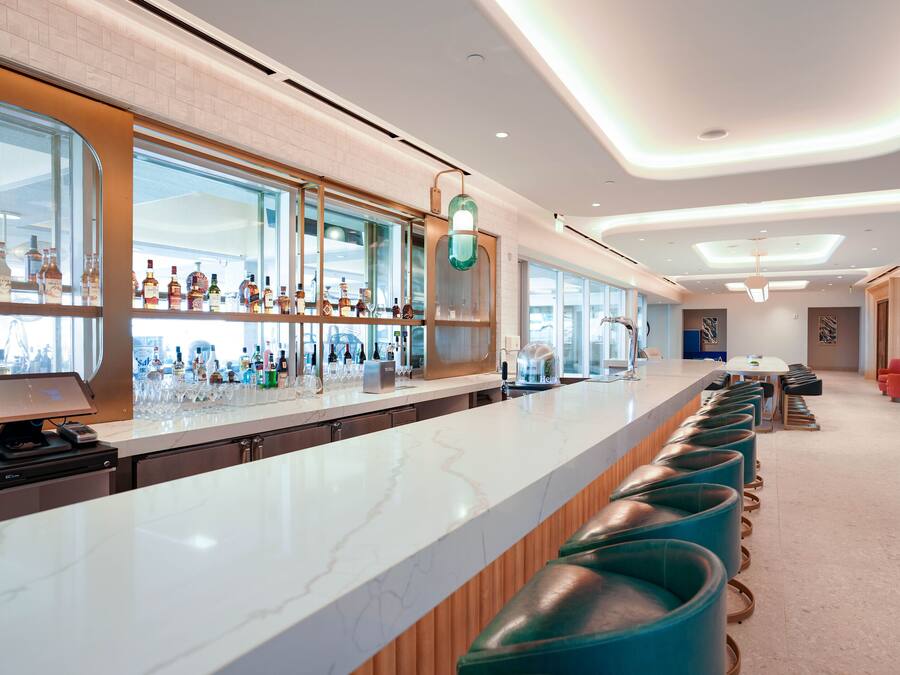 Zona de bar moderna con una barra larga, taburetes y una variedad de botellas.