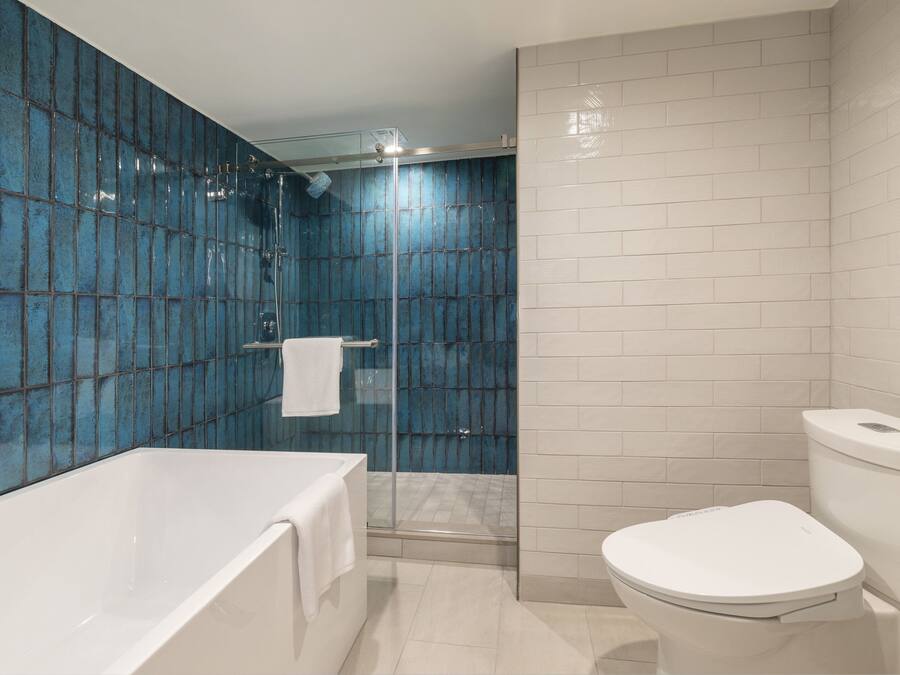 Un baño moderno con bañera, inodoro y zona de ducha con mampara de vidrio.