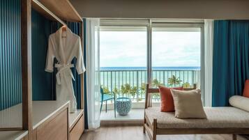 A hotel room with a balcony, a bed, a seating area, and a wardrobe.