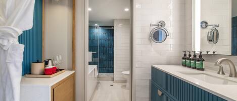 A modern bathroom with a white sink, blue vanity, and a glass shower enclosure.