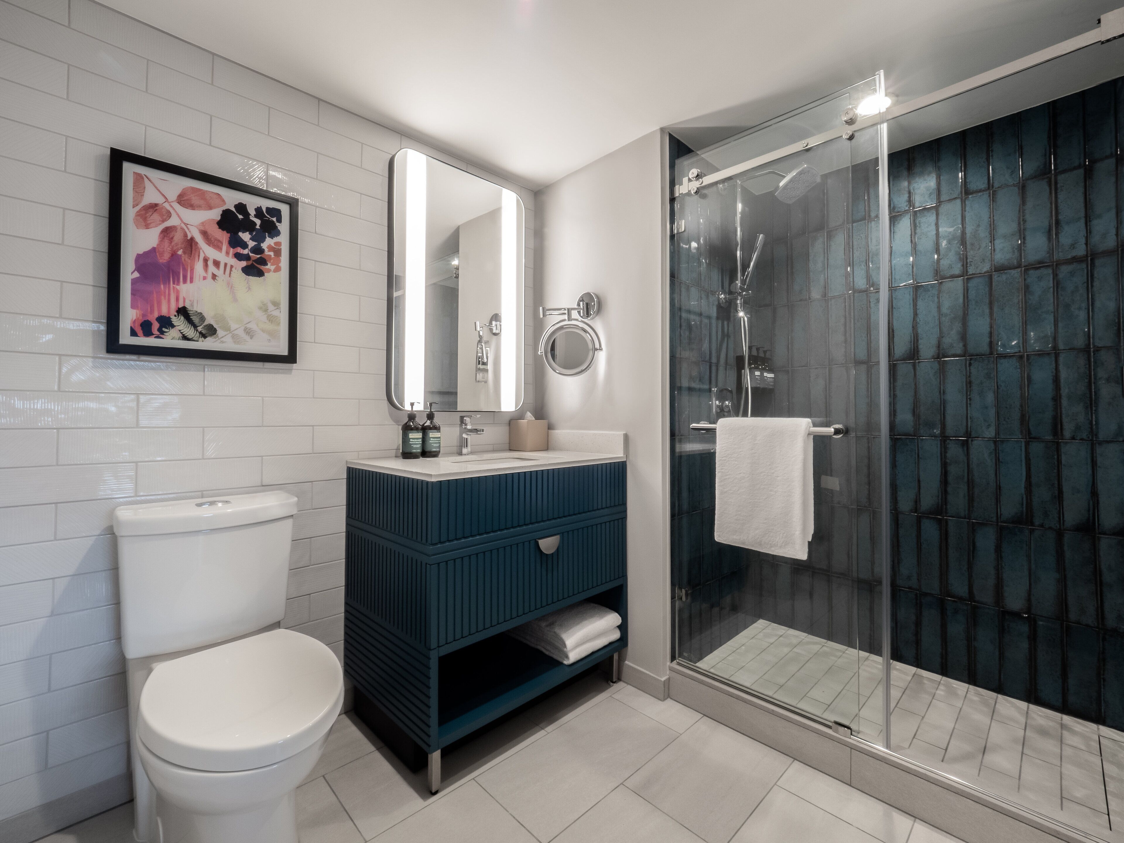 A modern bathroom with a toilet, a vanity with a mirror, and a glass-enclosed shower.