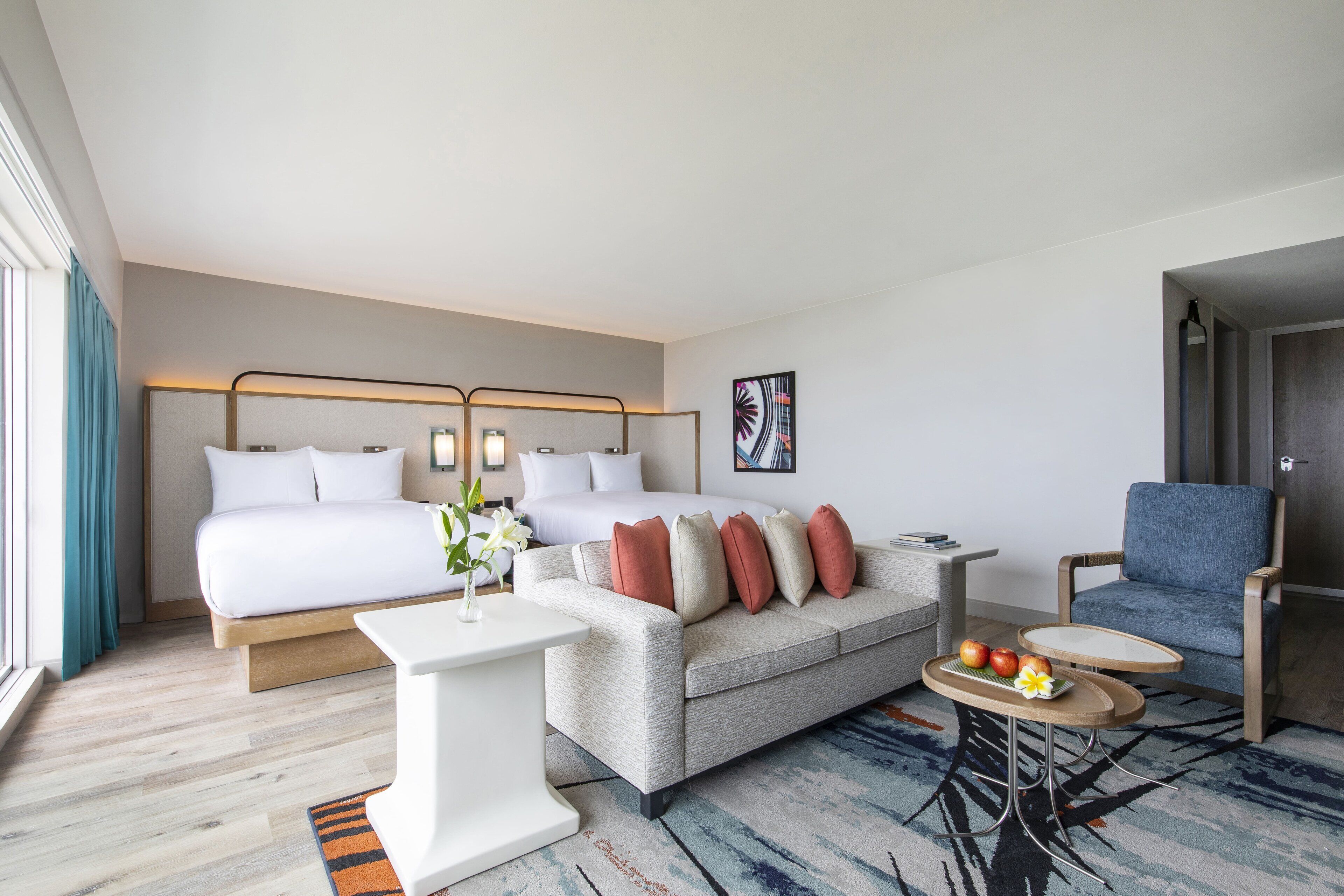 Une chambre d’hôtel moderne, équipée d’un lit, d’un canapé, d’une chaise, d’une petite table et d’un vase décoratif.
