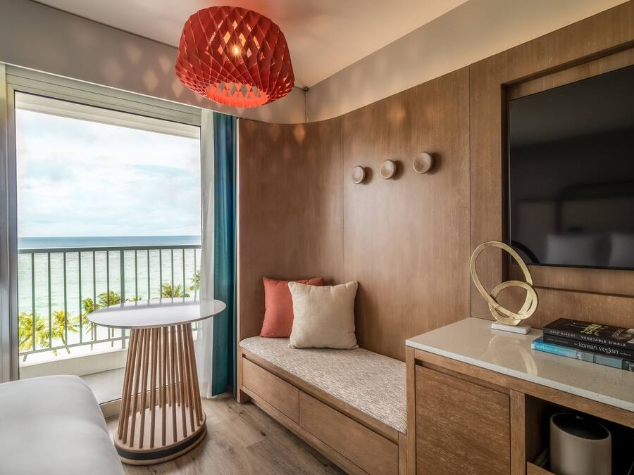 Una habitación moderna con un banco de madera, una mesa redonda y una lámpara colgante roja.