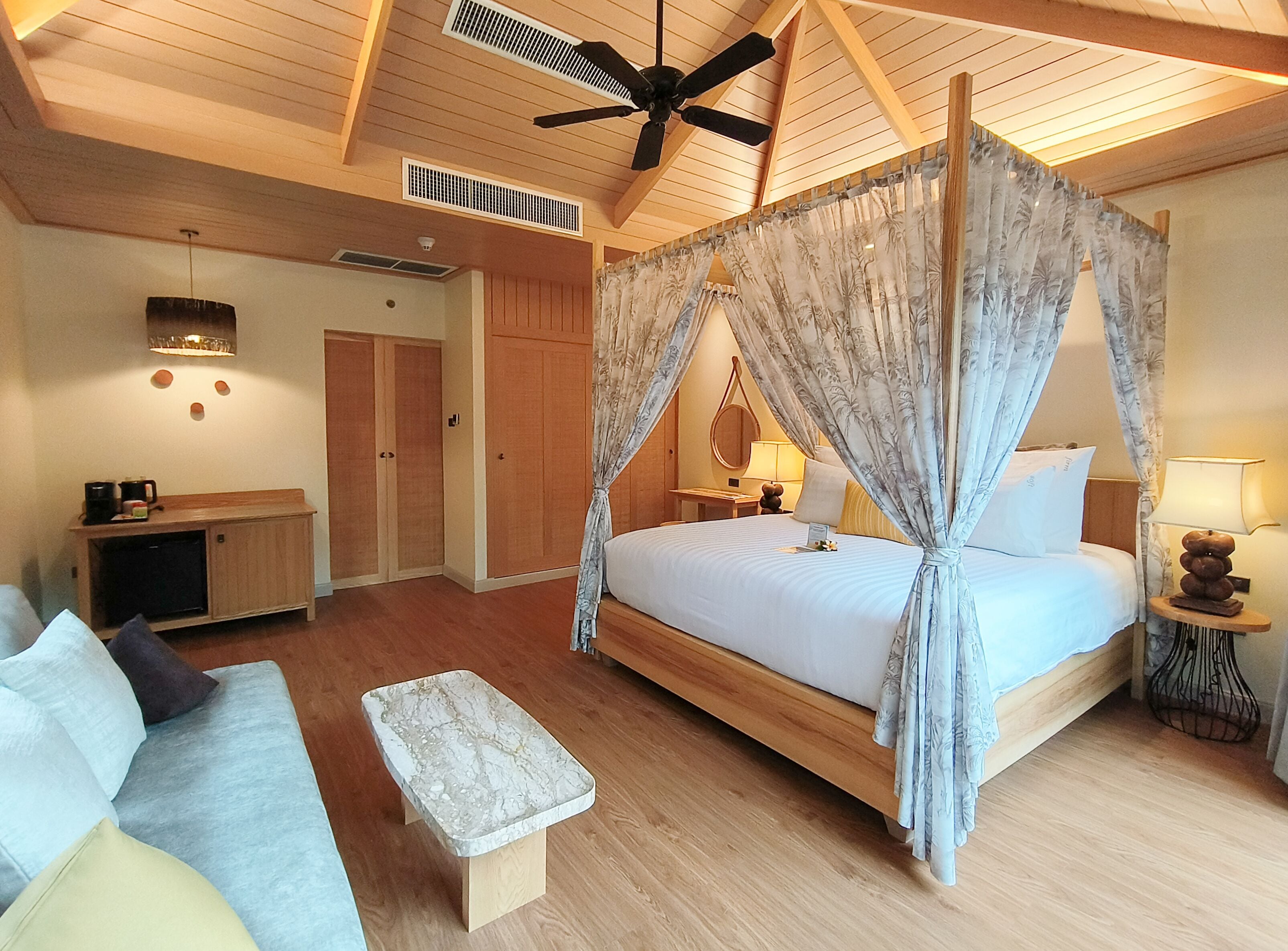 A bedroom with a canopy bed, wooden furniture, and a ceiling fan.