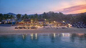 Un resort frente al mar con áreas de estar y comedor al aire libre, piscina y vista al océano.