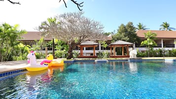 Relax by the serene pool surrounded by lush greenery and tropical plants.