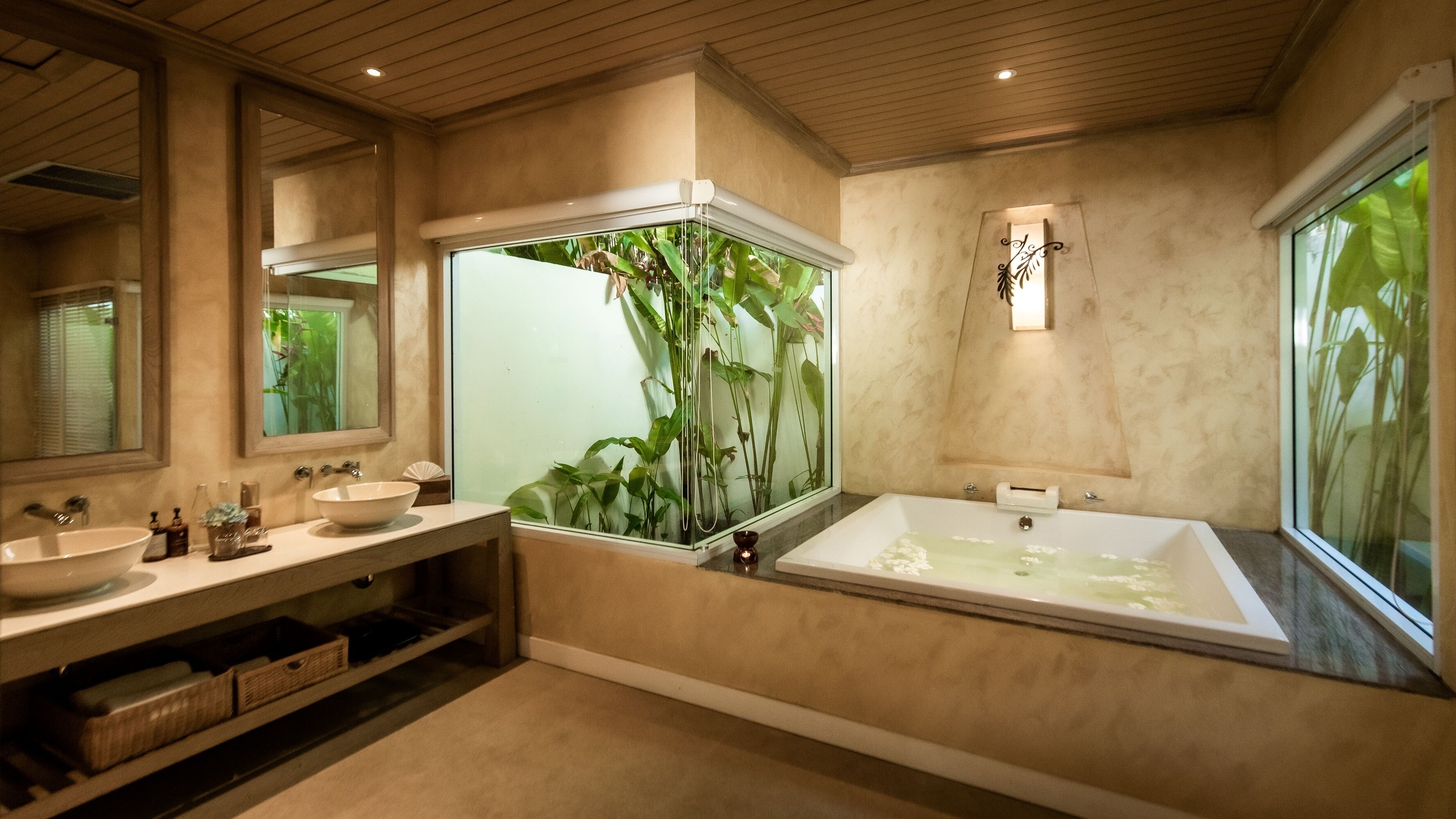 A modern bathroom with two sinks, a large bathtub, and a glass enclosure with plants.