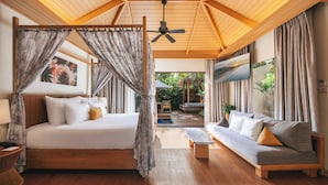 Un dormitorio con cama, sofá, ventilador de techo y vista al exterior.