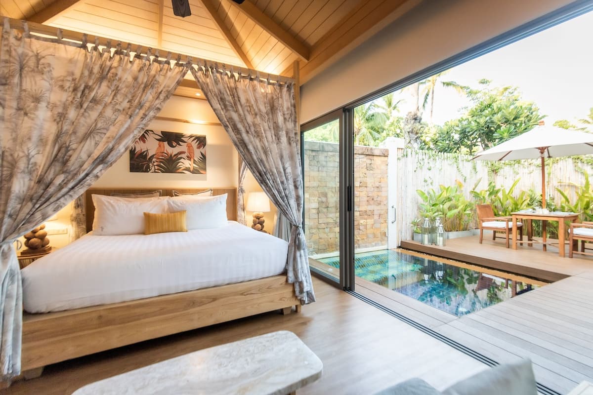 Un dormitorio con una cama de madera, vistas a una piscina y un patio amoblado.