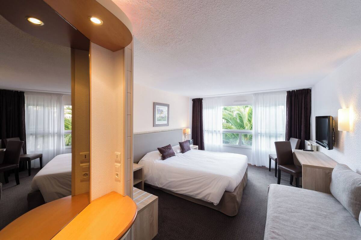 Une chambre d’hôtel équipée d’un lit, d’un bureau, d’une chaise, d’un canapé et d’une télévision.