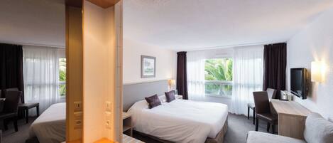 Ein Hotelzimmer mit Bett, Schreibtisch, Sessel, Sofa und Fernseher.