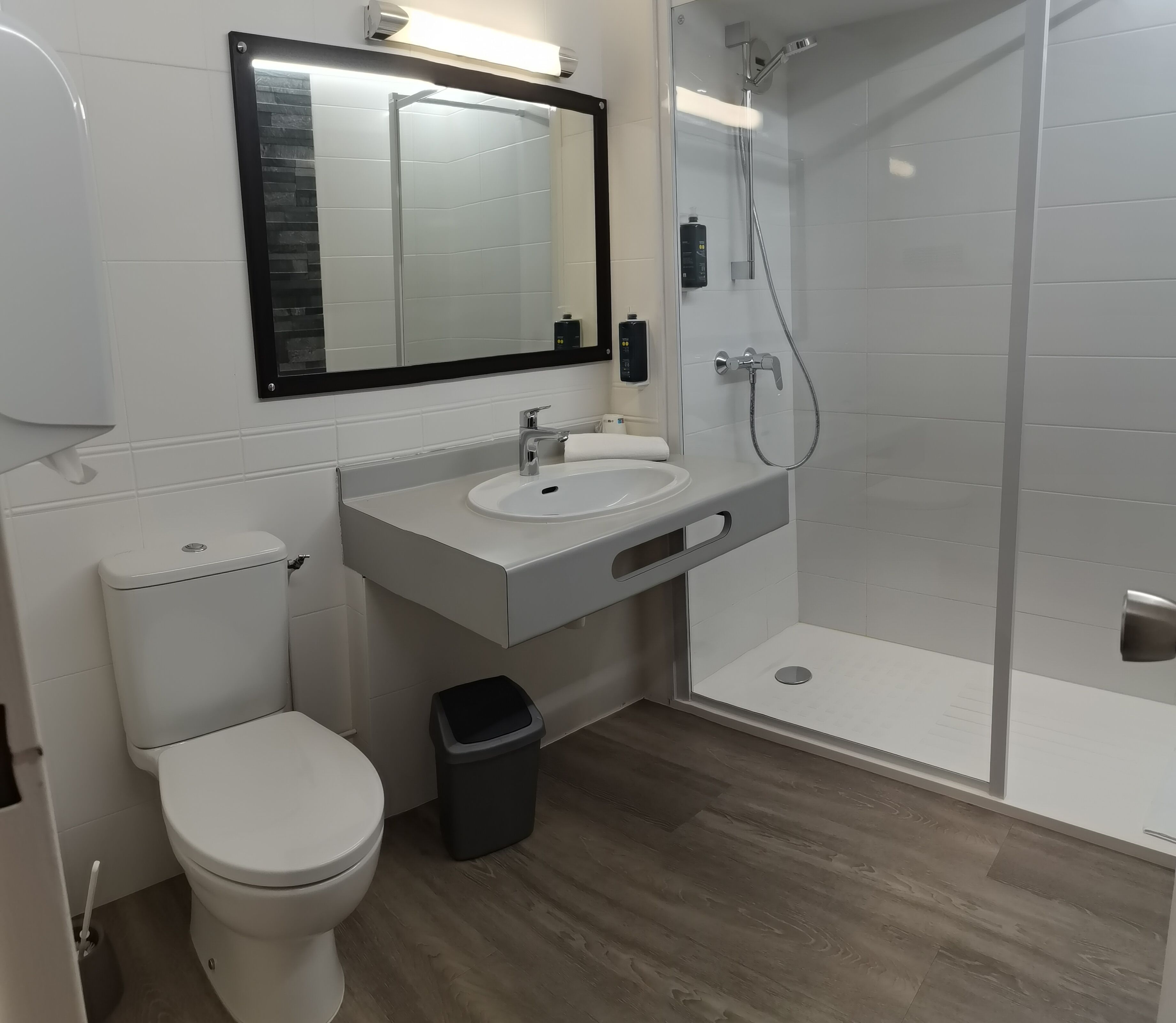 Uma casa de banho moderna com sanita, lavatório e chuveiro.