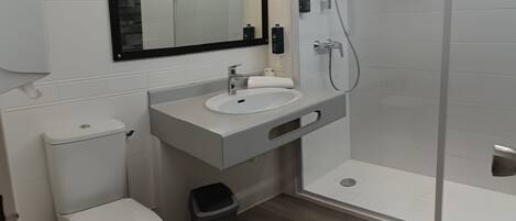 Uma casa de banho moderna com sanita, lavatório e chuveiro.