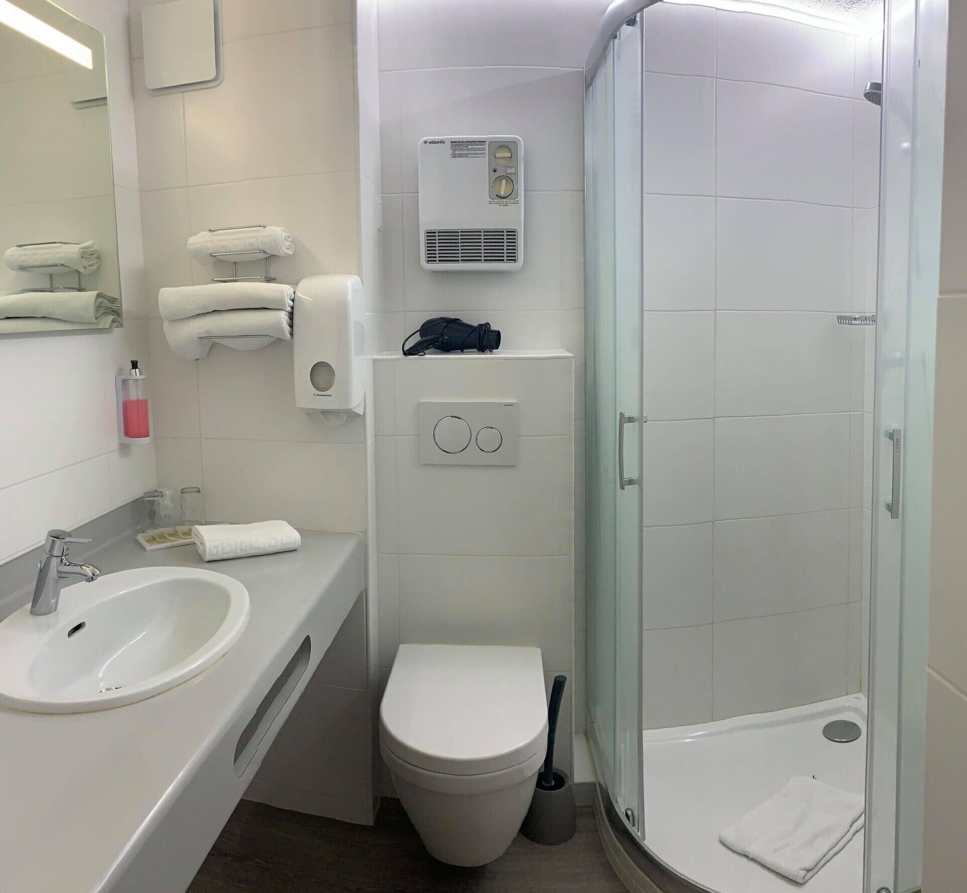 A modern bathroom with a sink, toilet, and glass-enclosed shower.