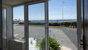 A view from inside a building with large windows overlooking a parking area and a body of water. - Hôtel de l’Océan Concarneau (Concarneau)