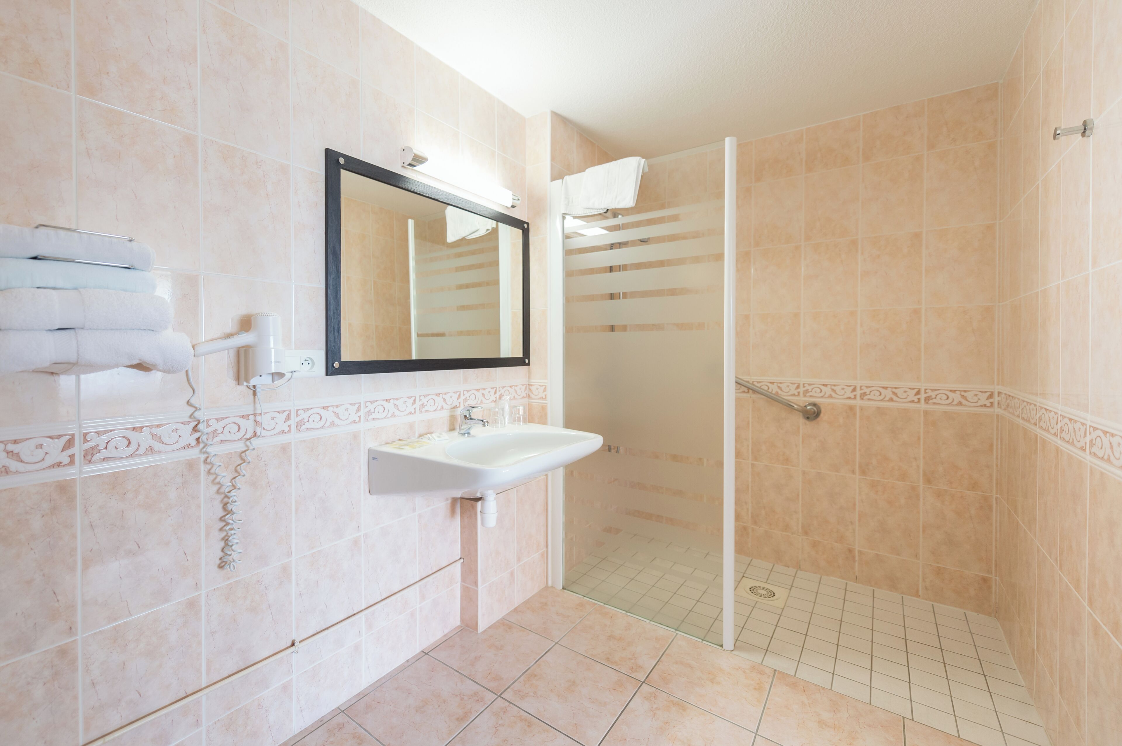 A bathroom with a sink, mirror, and shower.