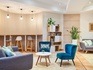 A modern living room with a sofa, armchairs, a small round table, and a bookshelf. - Aparthotel Adagio Access Nice Garibaldi (Nice)