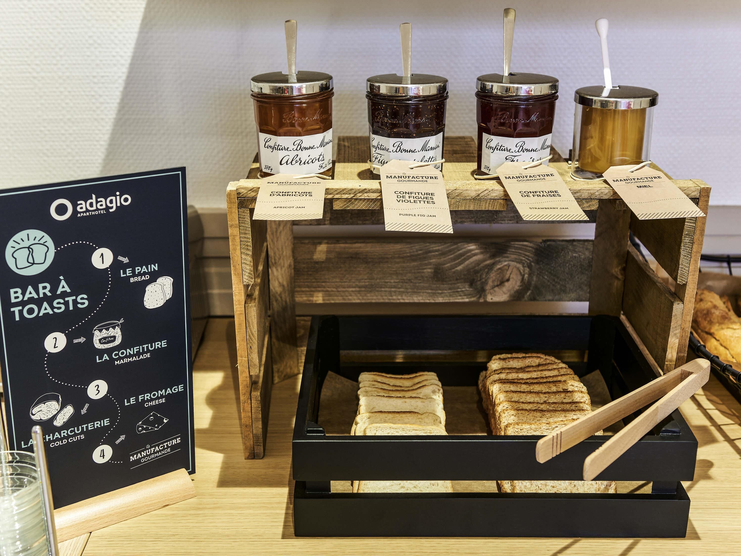 A display of jams and bread at a hotel breakfast counter.