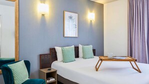 Une chambre d’hôtel comprenant un lit, une table de chevet, une chaise et une petite table.