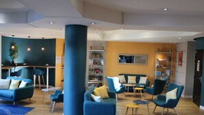 Un espace de détente moderne avec des canapés et des fauteuils bleus, une table basse et une bibliothèque.
