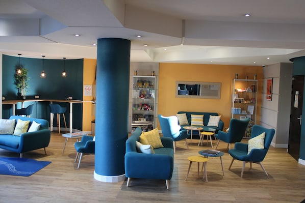 A modern lounge area with blue sofas and armchairs, a coffee table, and a bookshelf. - Aparthotel Adagio Access Nice Garibaldi (Nice)