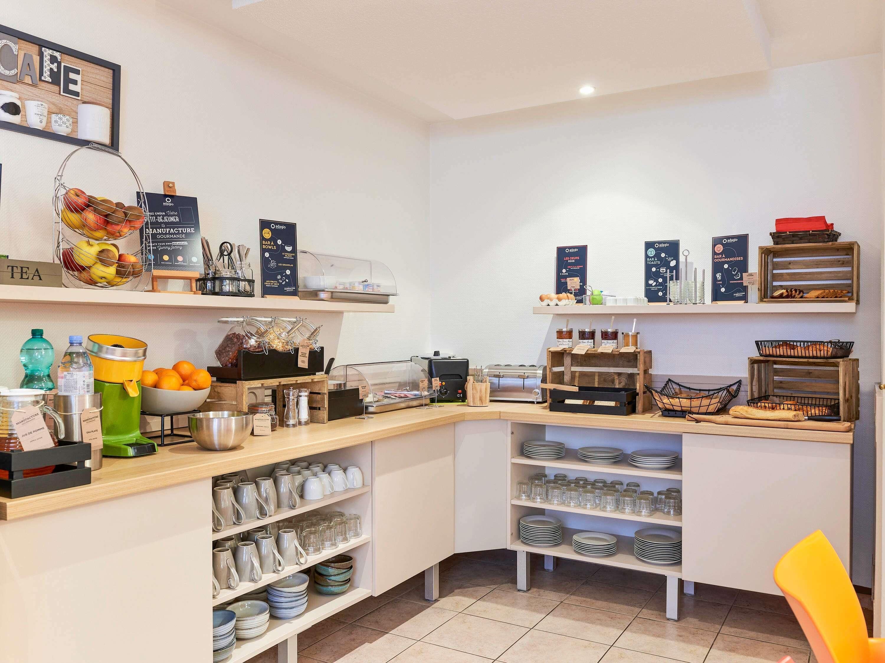Un café con un mostrador que exhibe té, café y pastelería. Hay estanterías con cristalería y una exposición de pan.