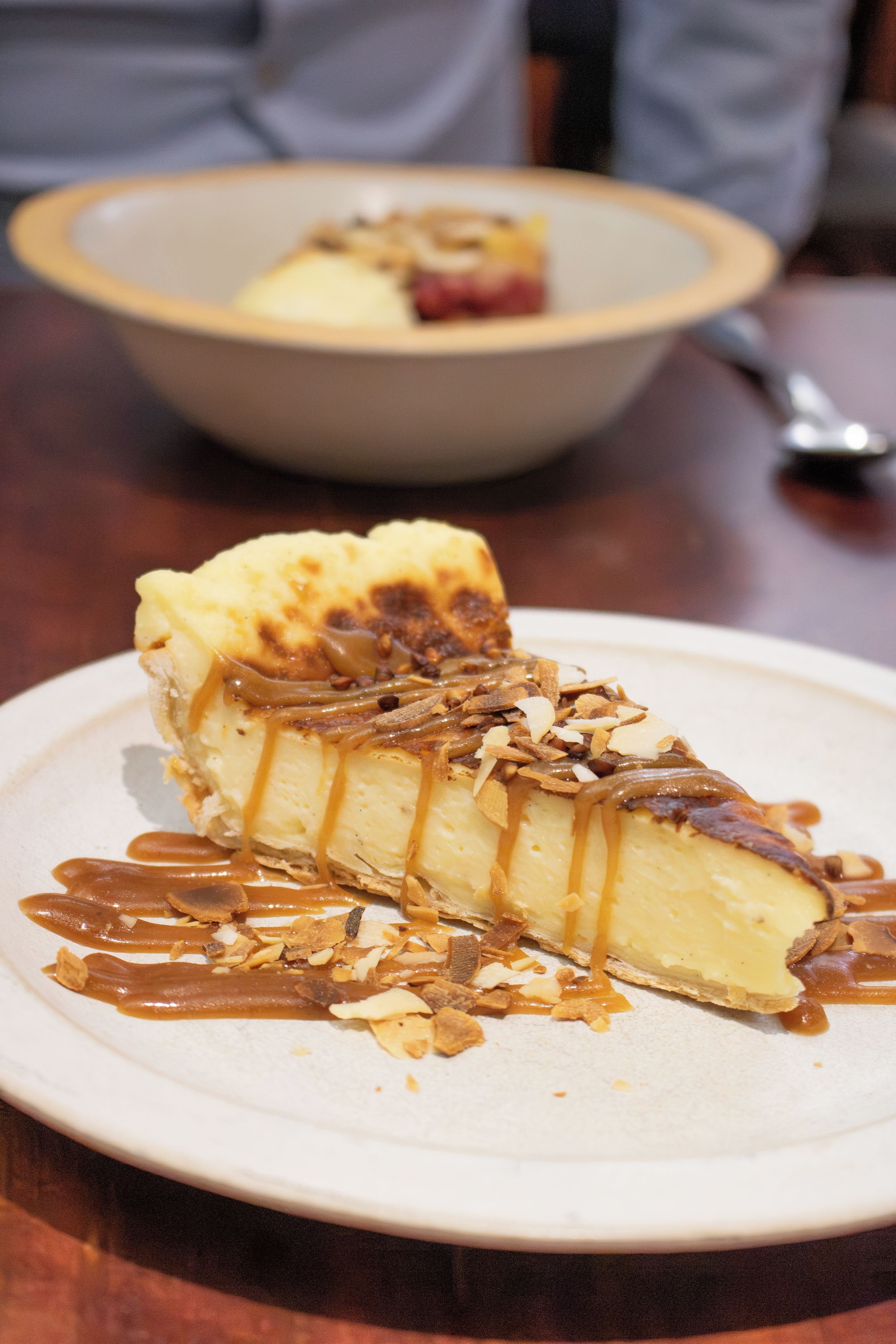 A dessert on a plate with caramel sauce and almonds.