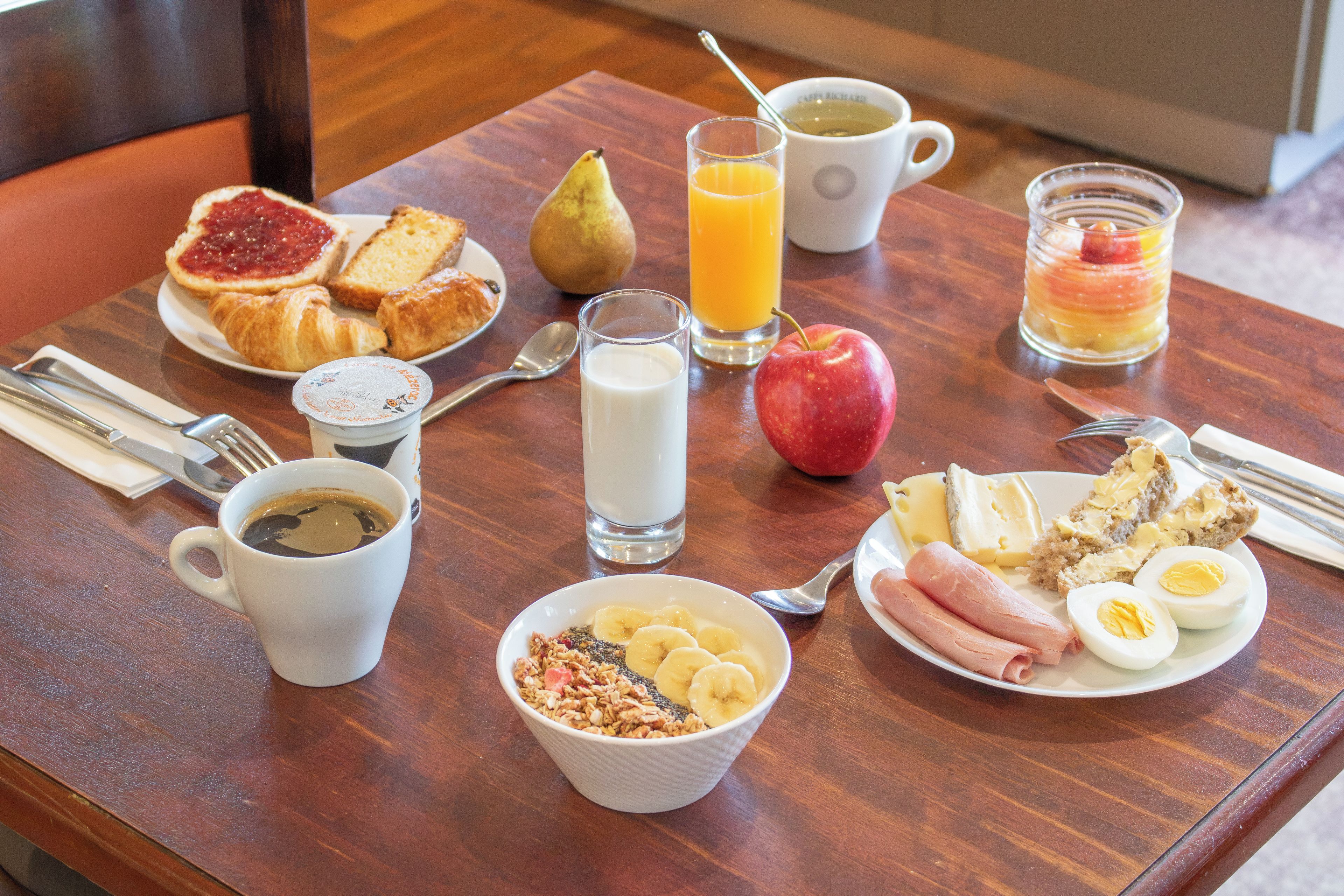 A breakfast table with various food items and drinks.