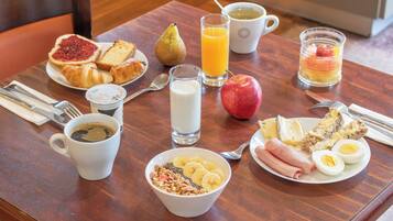 A breakfast table with various food items and drinks.