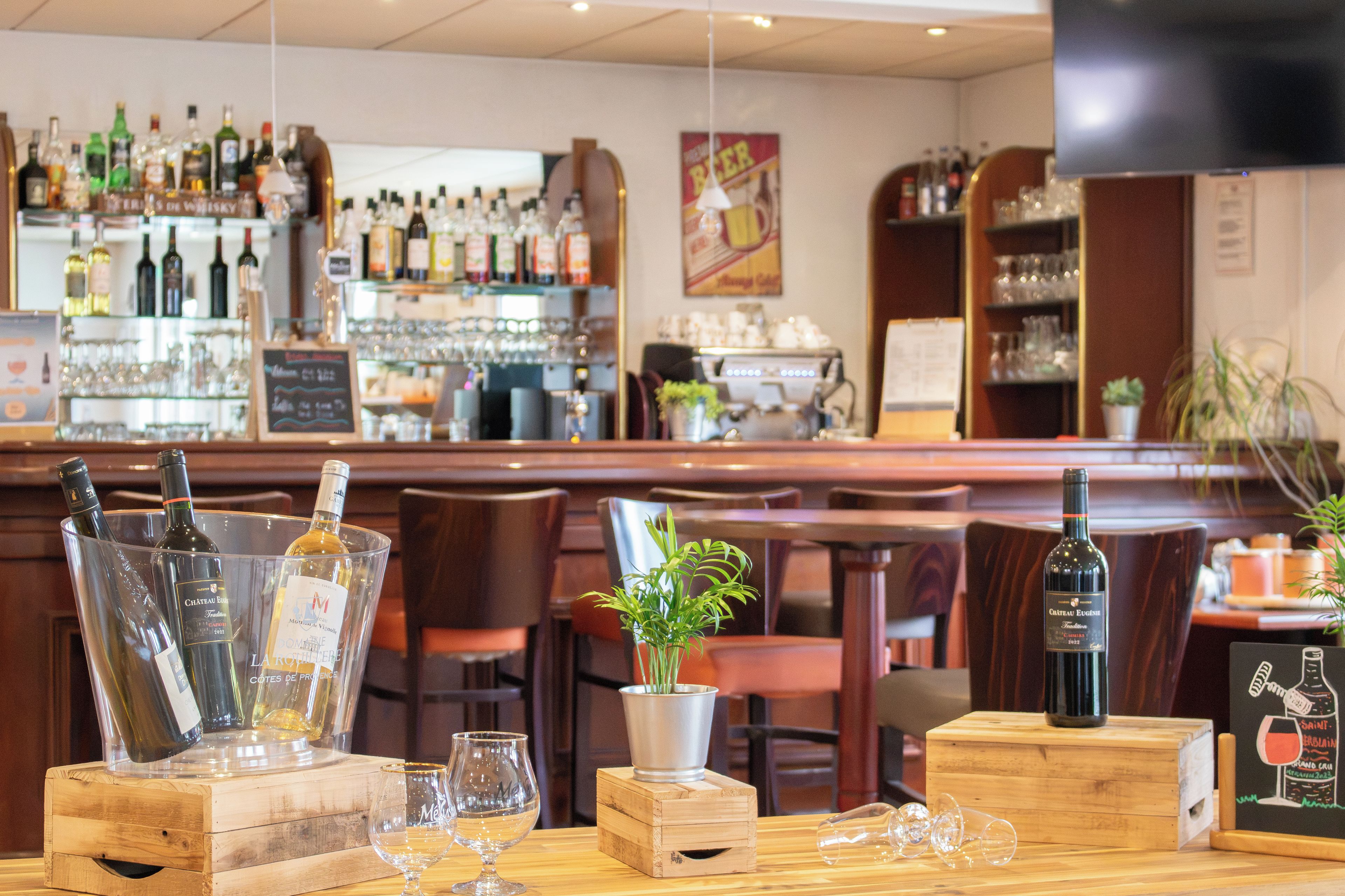 A bar area with bottles and glasses on display, wooden furniture, and a television screen.