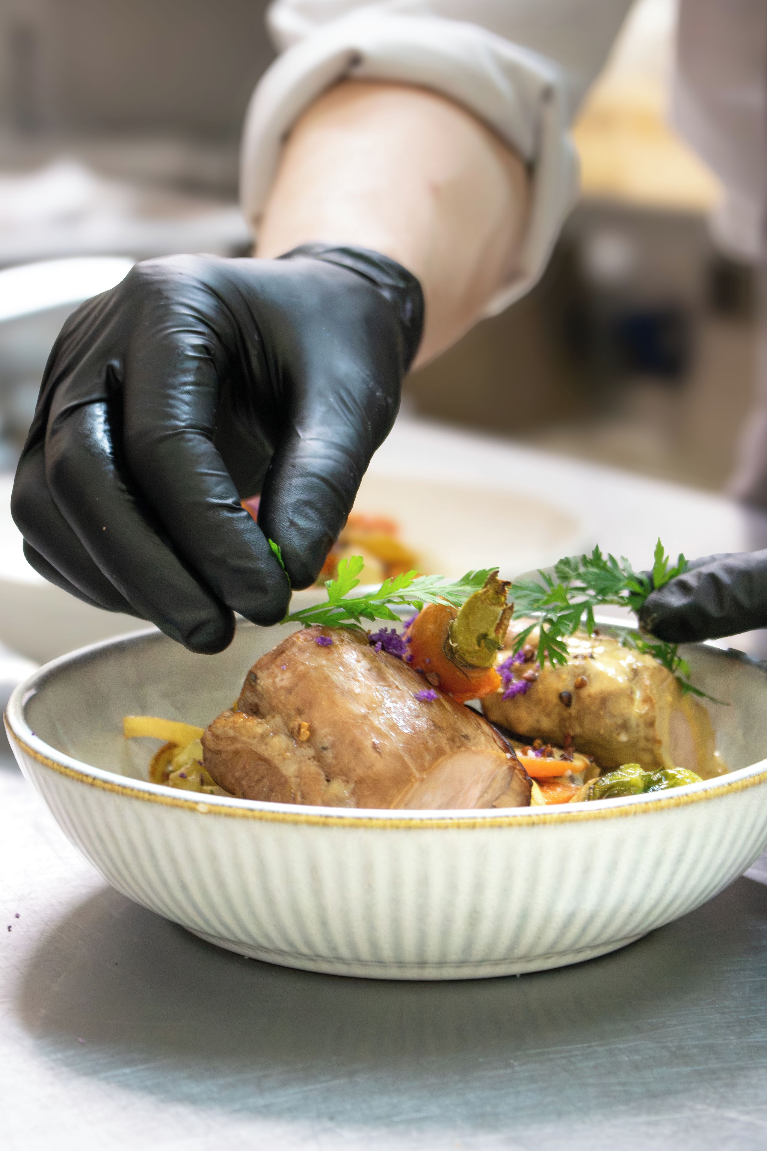 A person wearing black gloves preparing food in a bowl.