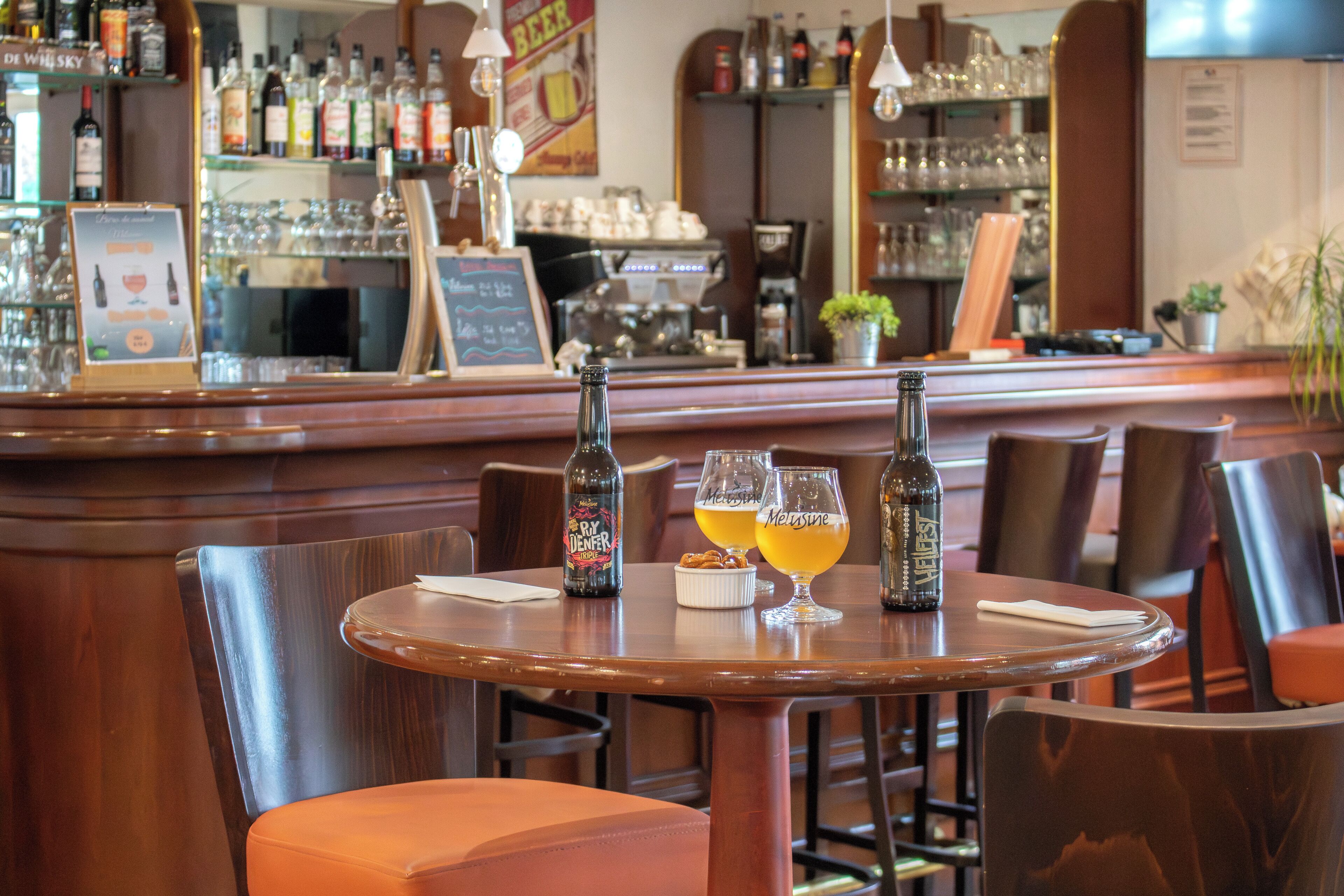 Un coin bar avec des meubles en bois, une bouteille de bière et des verres sur une table.