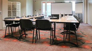 A conference room with a long table, chairs, a whiteboard, and a projector screen. - Brit Hotel Nantes St Herblain - Le Kerann (Saint-Herblain)