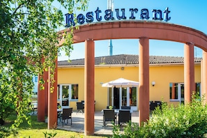 Un restaurante con letrero visible, mesas al aire libre y techo de tejas.