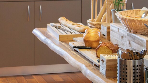 A breakfast buffet setup with bread, pastries, and beverages. - Brit Hotel Nantes St Herblain - Le Kerann (Saint-Herblain)