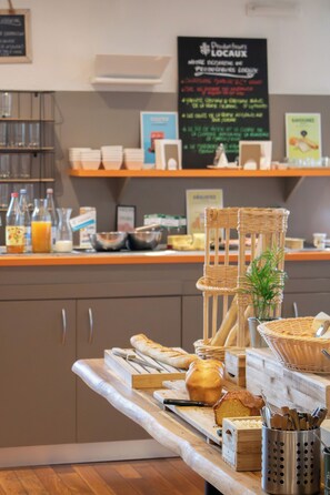 Un buffet de petit-déjeuner proposant du pain, des viennoiseries et diverses boissons.
