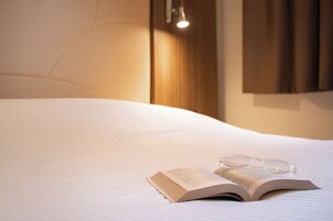 Una cama bien hecha con un libro y gafas encima.