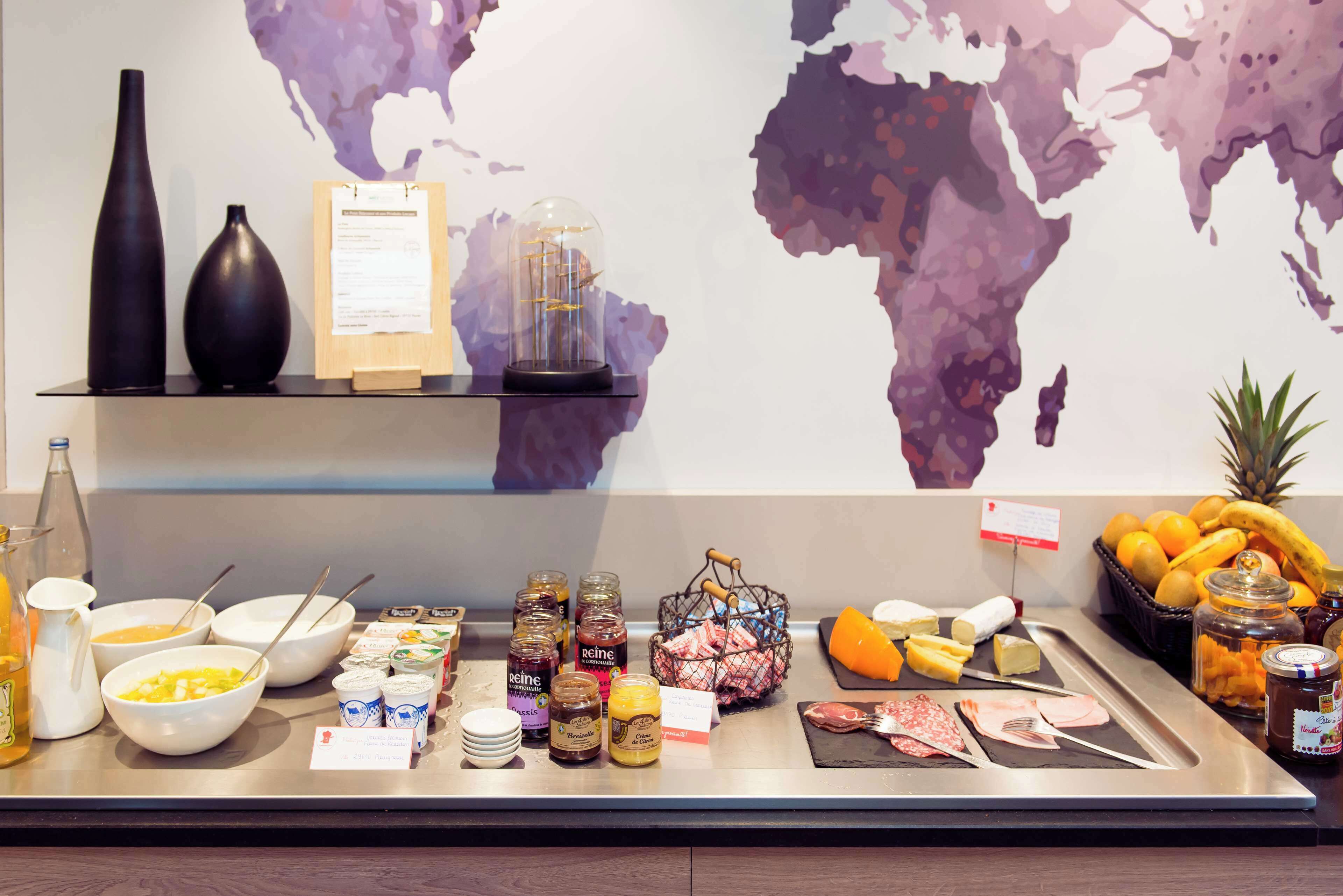 A buffet setup with various food items, condiments, and a world map on the wall.