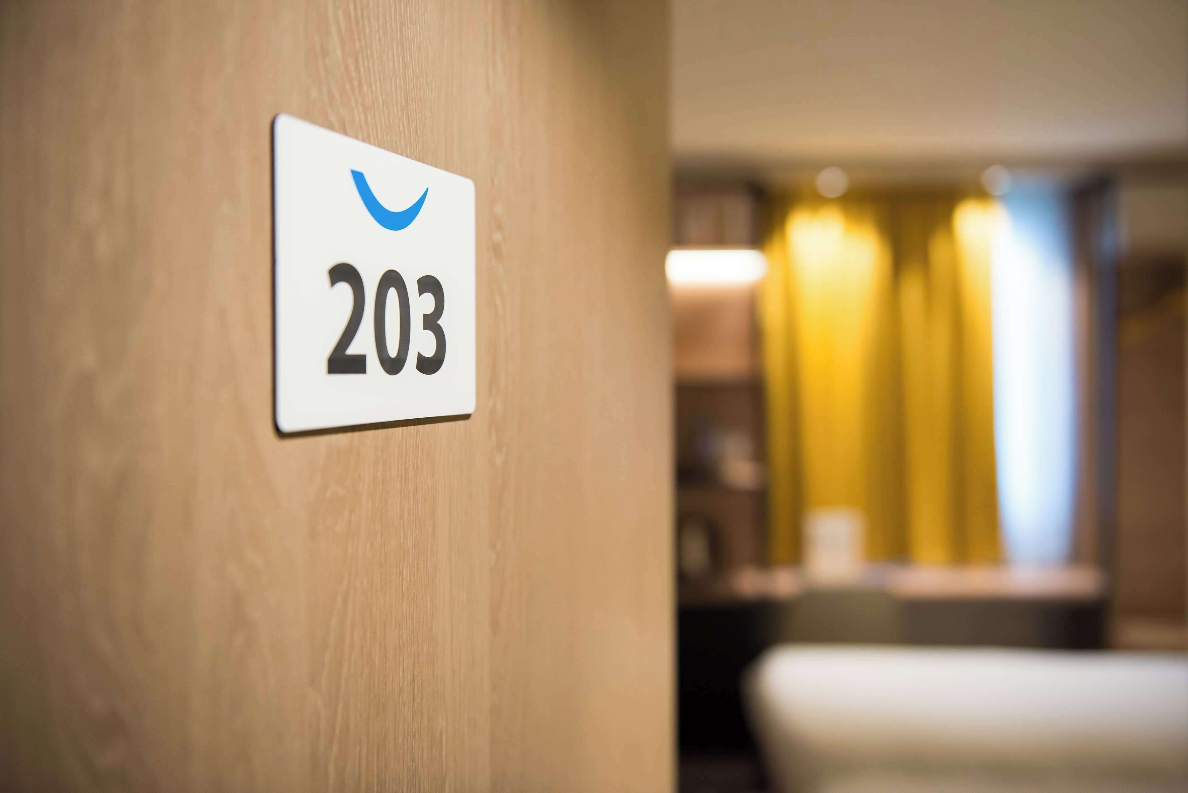A hotel room number sign, 203, on a wooden wall.