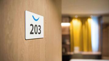 A hotel room number sign, 203, on a wooden wall.