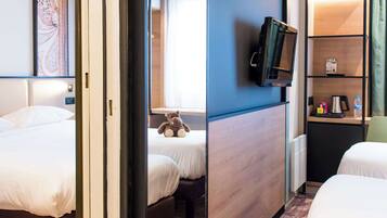 A hotel room with two beds, a television, a desk with a computer, and a bookshelf.