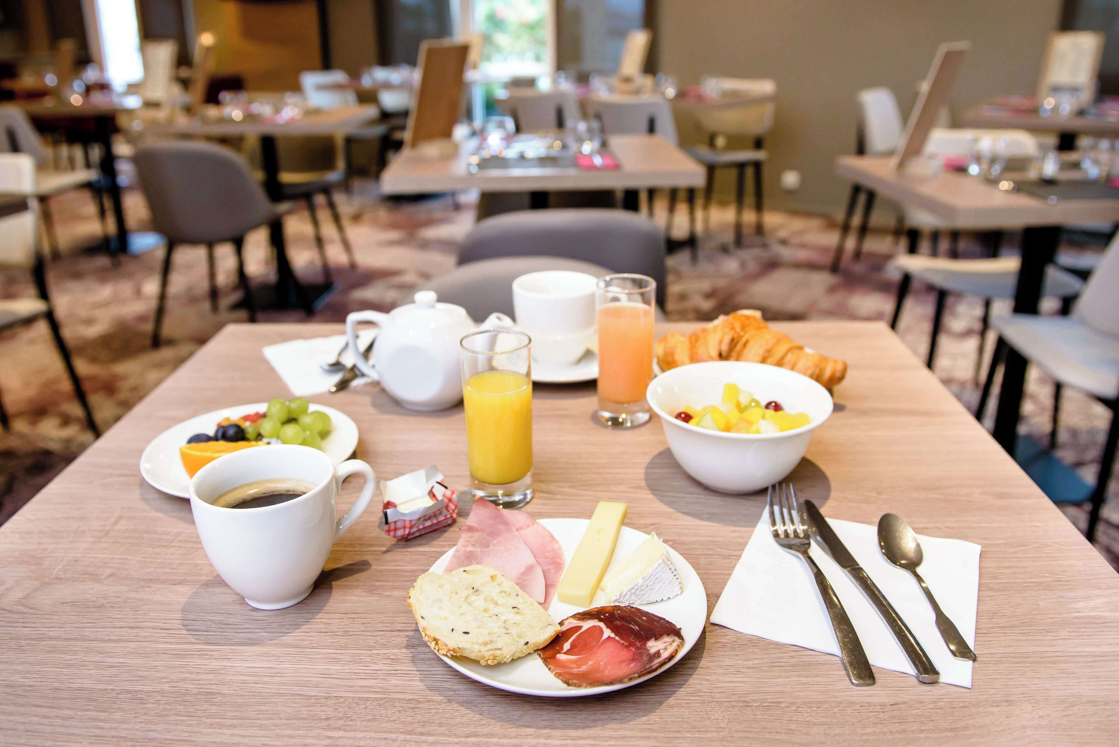 A breakfast setting with a plate of food, a cup of coffee, a glass of orange juice, and a bowl of fruit.