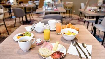 A breakfast setting with a plate of food, a cup of coffee, a glass of orange juice, and a bowl of fruit.