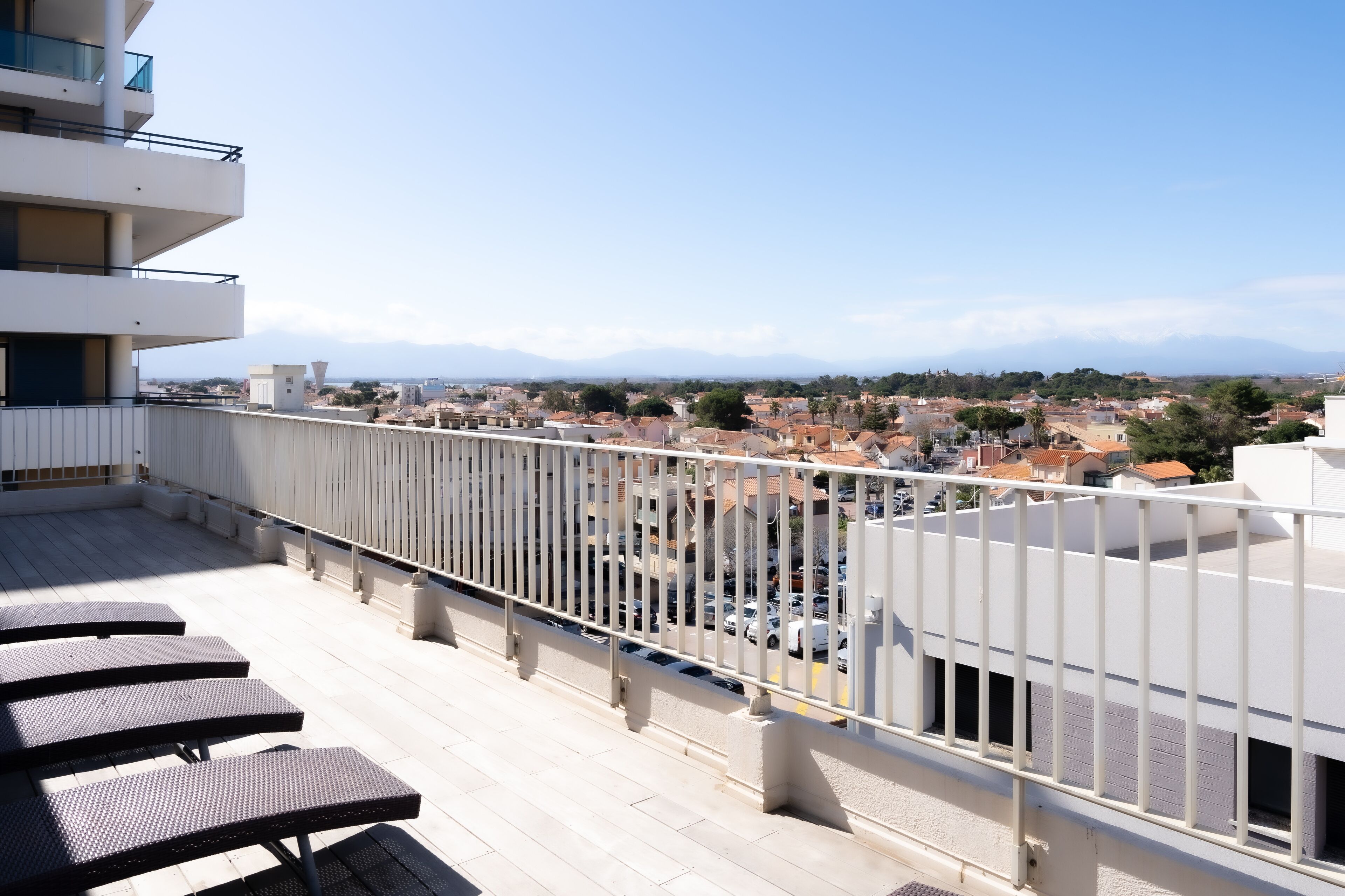 Terraza en la azotea con mobiliario exterior y vistas a la ciudad y montañas.